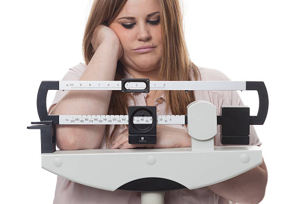 Sad and worried woman on a medical weight scale. white background.